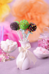 Sweet cake pops in vase on table on bright background