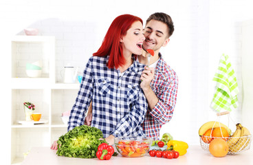 Happy couple preparing  vegetable salad in kitchen