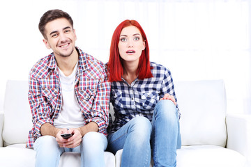 Young couple watching television at home