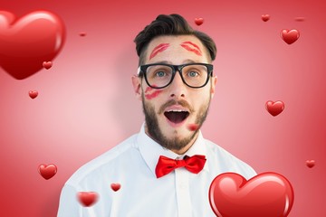 Composite image of geeky hipster with kisses on his face