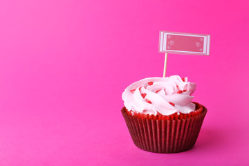 Delicious cupcake with inscription on pink background
