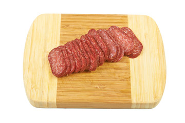 Slises of sausage on a wooden board isolated on white