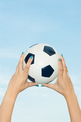 Woman holding a soccer ball up into the sky