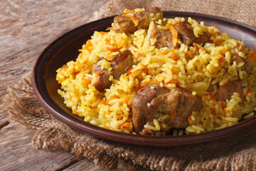 pilaf with meat and vegetables close up on a plate. horizontal