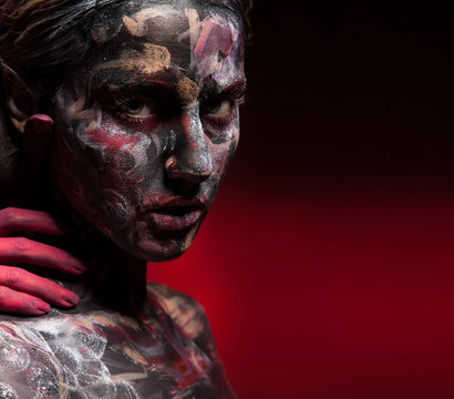 Woman face with colorful bodyart and scarry red hand