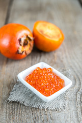 Bowl of red caviar on the wooden table