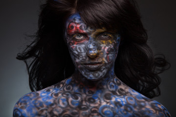 Brunette woman in dark colourful paint on skin. Face art.