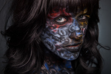 Brunette woman in dark colourful paint on skin. Face art.