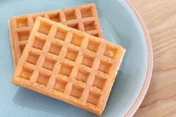 Delicious sweet waffle in ceramic plate on wood table
