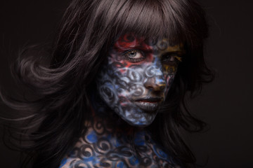 Brunette woman in dark colourful paint on skin. Face art.