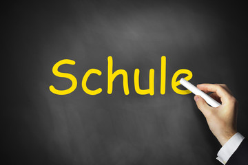 Hand schreibt Schule auf schwarze Tafel