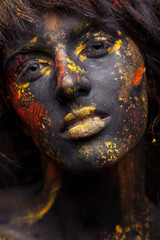 dark portrait of woman in black paint with yellow smudges
