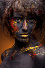 dark portrait of woman in black paint with yellow smudges