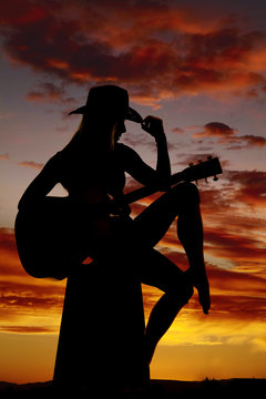 silhouette of a woman with a guitar hand on hat