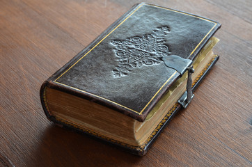 engraved old book with lock on wood table