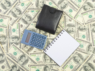 Calculator and notebook on a dollars background
