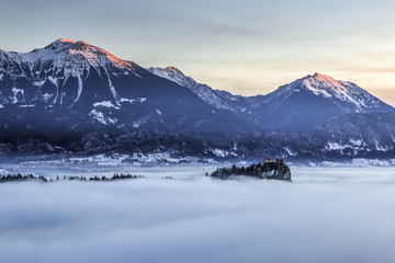 Fototapeta na wymiar View over the fog covered bled lake to the alps at dawn