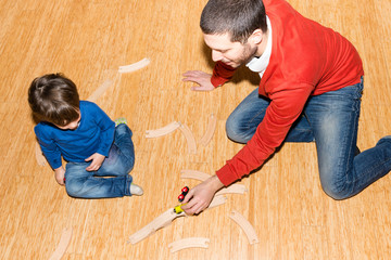 Baby and father playing with train on the floor