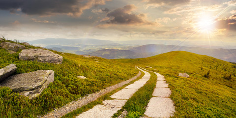 road on a hillside near mountain peak at sunset