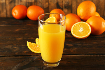 Glass of orange juice with slices on wooden table background