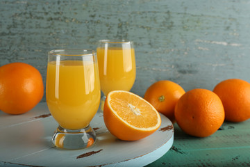 Glass of orange juice with slices on color wooden background