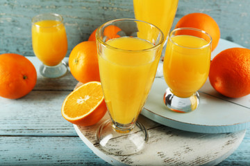 Glass of orange juice with slices on color wooden background