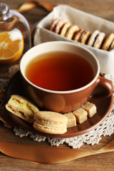 Colorful macaroons with cup of tea on wooden background