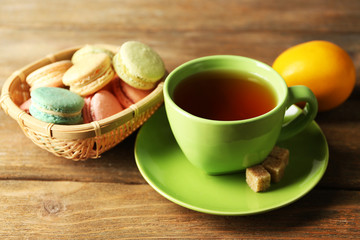 Colorful macaroons with cup of tea on wooden background