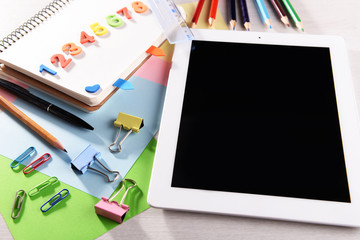 Tablet PC with office supplies on desktop background