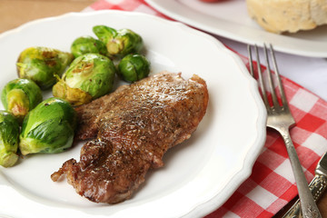 Roasted meat and vegetables on plate, on wooden table