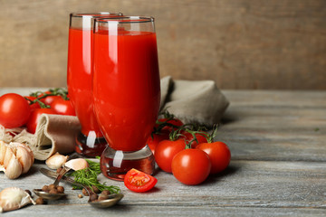 Glasses of tasty tomato juice and fresh tomatoes on wooden