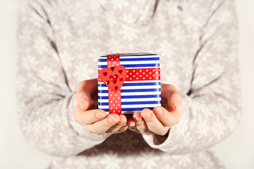 Female hands holding present box with ribbon on light