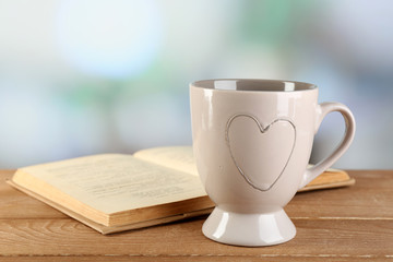 Cup of tea and book on table, on bright background