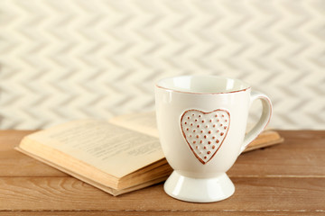 Cup of tea and book on table, on light background