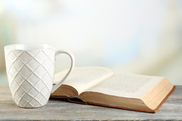 Cup of tea and book on table, on light background