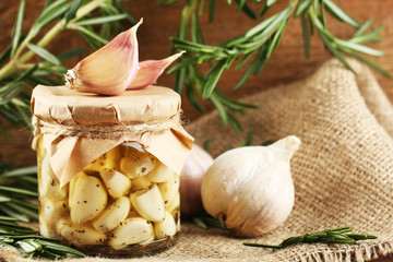 Canned garlic in glass jar on wooden background