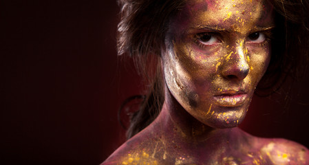 Girl with gold paint on face with face art and body art
