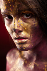 Girl with gold paint on face with face art and body art