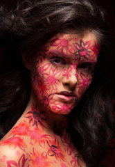 Pretty woman with flowers face art. Red flowers on face.