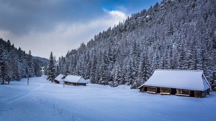 Old wooden cottages in winter mountains