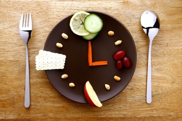 Fruits, veggies, nuts, crackers on a plate arranged like a clock