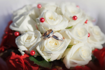Obraz na płótnie Canvas Gold wedding rings on a bouquet of beige roses