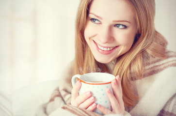 happy woman is under blanket and  cup of coffee