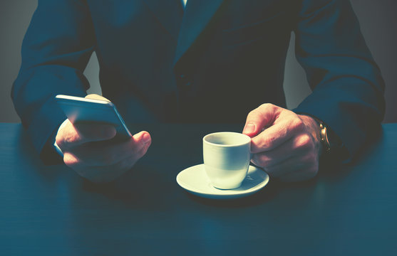 Phone And Cup Of Coffee In Hands Of  Businessman