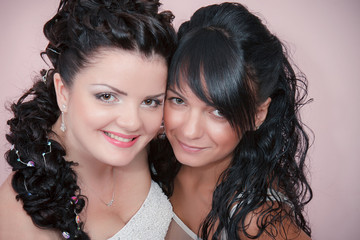 Beautiful bride with her pretty bridesmaid in studio