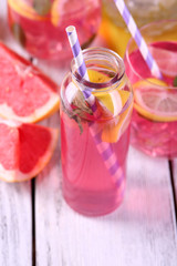 Pink lemonade in glasses and bottle on table close-up