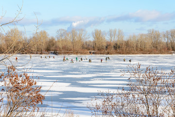 Kiev, Ukraine, the Dnieper river is frozen. Fishermen are waiting to catch some fish under the low winter sun