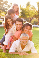 Fototapeta premium Multi Generation Family Lying In Pile Up On Grass Together