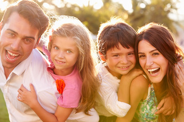 Parents Giving Children Piggybacks In Park
