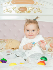 Small caucasian child girl play with toys on the bed at home